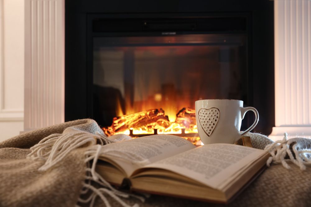 Cup,Of,Hot,Drink,And,Book,On,Blanket,Near,Fireplace