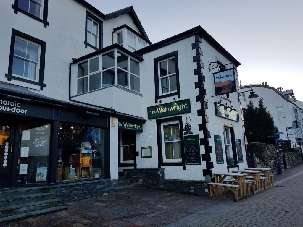 Exterior of a black and white fronted pub with tables and benches outside