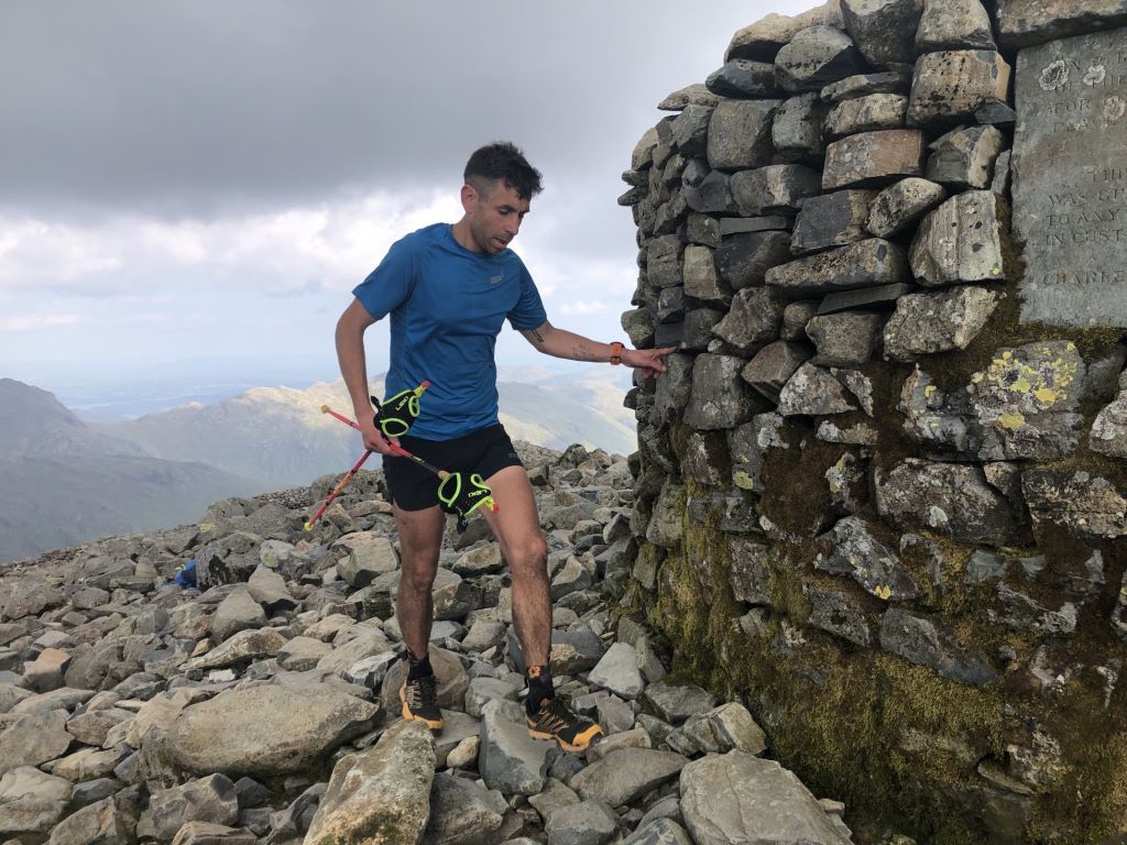 Runner touching mountain summit cairn