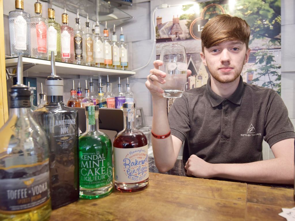 Young man behind bar with bottles of spirits in front of him