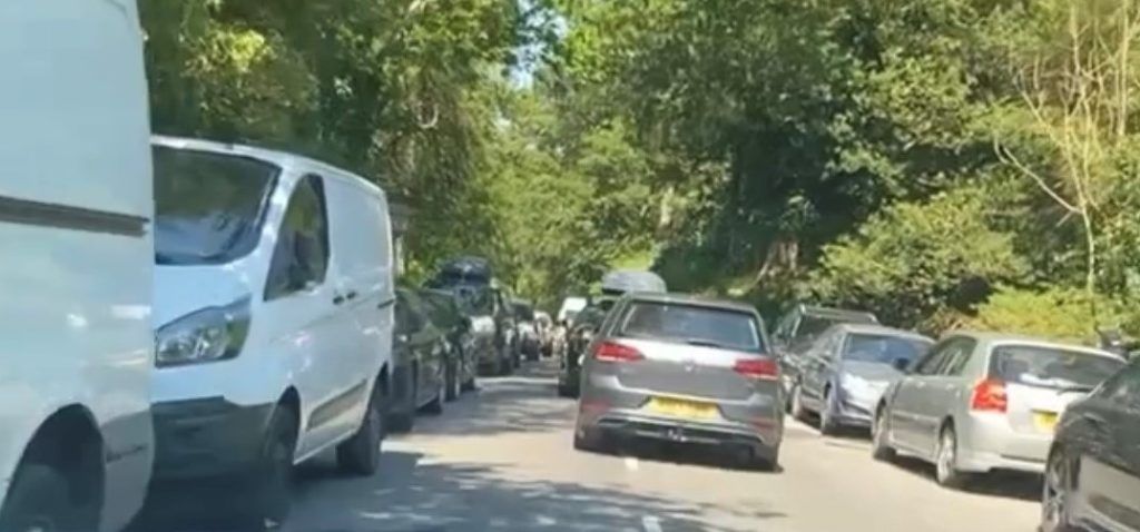 Narrow country road with vehicles parked on both sides 