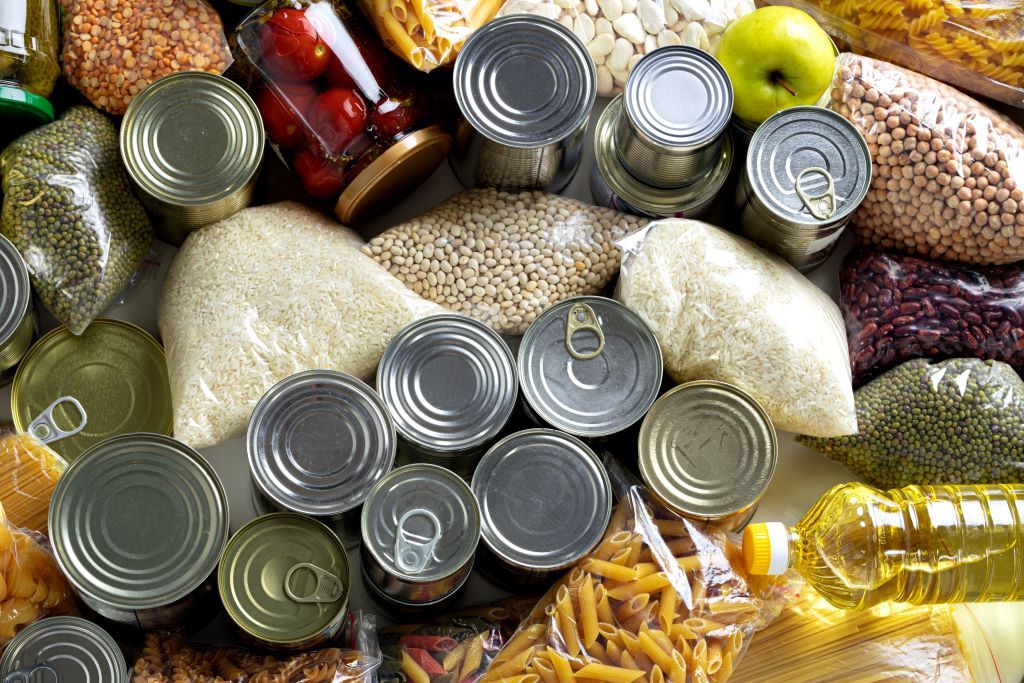 Tabletop of closely packed tins of food and packets of rice, pasta and pulses 